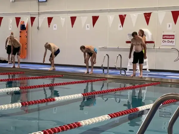 Swimmers lined up on the pool deck preparing to dive at a Turners swim meet