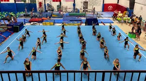 A large gymnastics class working in rows across the floor mat