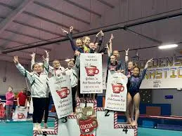 An Aurora Turners gymnastics team celebrating on the podium with award banners