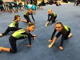 Young Aurora Turners gymnasts stretching on the floor mat during practice