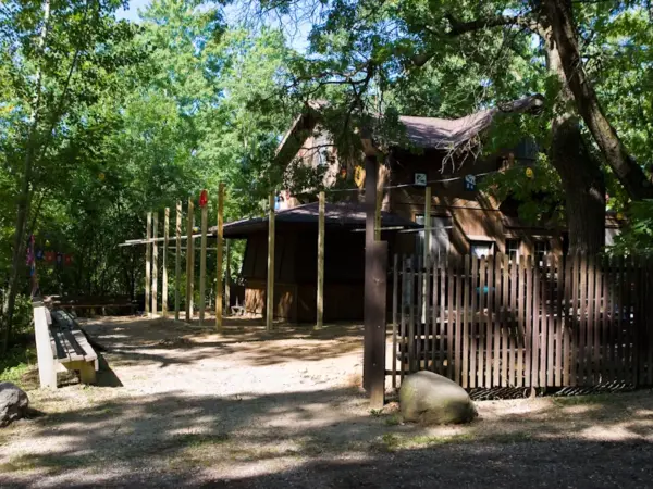 The wooden camp clubhouse surrounded by mature trees on a sunny day