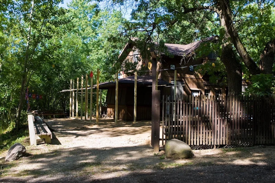 The wooden camp clubhouse surrounded by mature trees on a sunny day