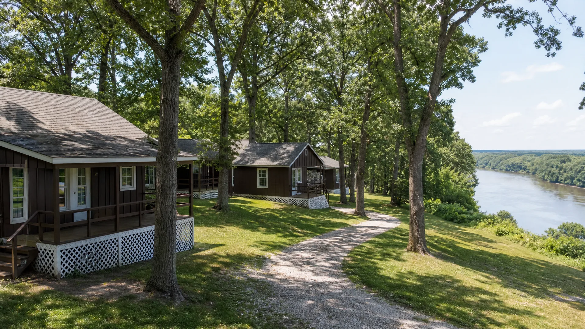 Brown-sided cottages with white lattice skirting standing among oaks on the bluff above the Fox River at Illinois Turners Camp