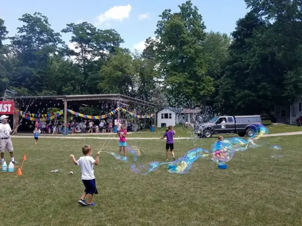 Children chasing giant soap bubbles on the lawn during Family Fest