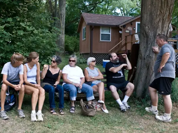 A group of members sitting and talking on a bench outside a camp cottage