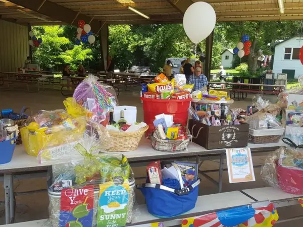 Raffle gift baskets and balloons laid out on tables under the camp pavilion
