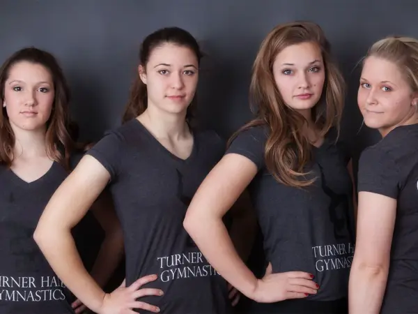 Four Turner Hall Gymnastics team members and a coach in team shirts