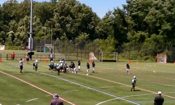 Youth football teams lined up during a game on a turf field
